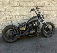 a black motorcycle parked in front of a brick wall