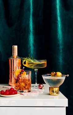 a table topped with drinks and fruit next to a glass filled with ice cubes