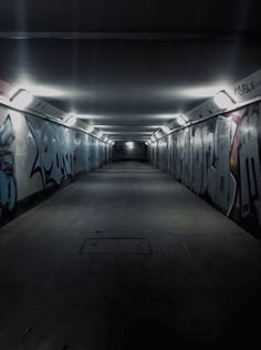 an empty parking garage with graffiti all over the walls and floor, along with lights on either side