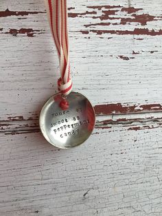 a metal spoon with a red and white ribbon hanging from it's side on a wooden surface