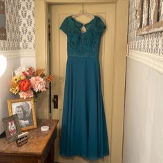 a blue dress hanging on a door in a room with flowers and an old photograph