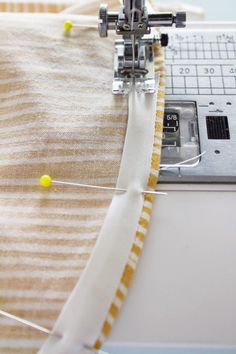 the sewing machine is stitching fabric with yellow pins on it's needle and thread