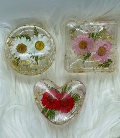 three glass plates with flowers on them sitting on a white furnishing area next to each other