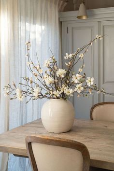 a white vase filled with flowers on top of a wooden table