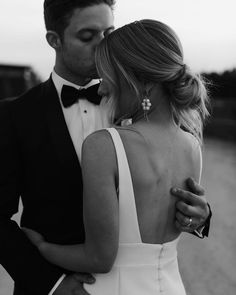 a man in a tuxedo and woman in a white dress are embracing each other