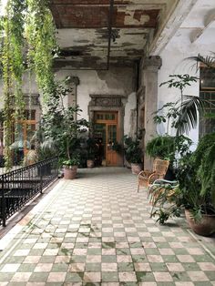 an old building with potted plants on the front and side porchs, along with a checkered tile floor