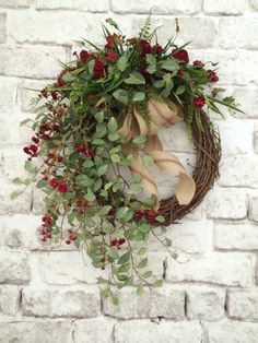 a wreath with red berries and green leaves hanging on a brick wall