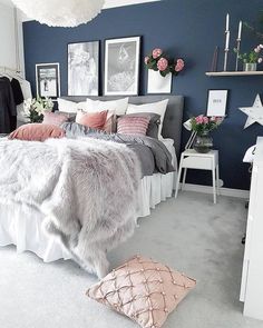 a bedroom with blue walls and white carpeted flooring is decorated in pink and grey tones