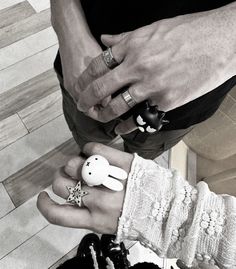 two people standing next to each other with rings on their fingers and one holding an object in the other's hand