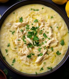 a bowl filled with soup and garnished with parsley on top, surrounded by lemons