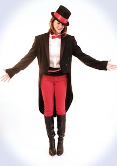 a woman dressed in red pants and a top hat with her hands out to the side