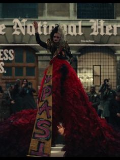 a woman in a red dress is standing on the street