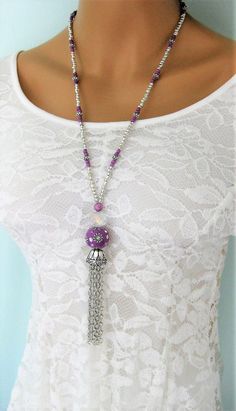 Long Silver and Purple Beaded Necklaces with Tassel handmade by Ralston Originals. These beaded necklaces come in your choice of Styles. I made the first purple tassel necklace (pictures 1 - 4) with a large purple crackle glass bead, a large antique silver metal bead on top of it, followed by a blue ceramic bead with antique silver metal bead caps surrounding it. The beaded chain is made with silver seed beads, purple seed beads, and a purple and blue bead. I made the tassel with silver metal ch Bohemian Long Tassel Necklace For Party, Bohemian Tassel Necklace With Beaded Chain, Bohemian Beaded Dangle Tassel Necklace, Bohemian Purple Beaded Necklace With Dangling Beads, Necklace Pictures, Silver Beaded Necklace, Assemblage Necklace, Beaded Tassel Necklace, Blue Beaded Necklace