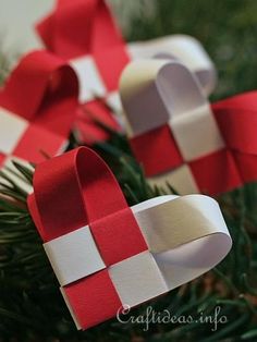 two red and white paper hearts hanging from a christmas tree with ribbon on it's ends