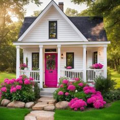 a white house with pink front door and flowers on the steps leading up to it