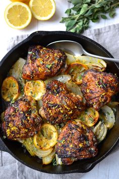 chicken thighs with onions and lemons in a cast iron skillet on a table