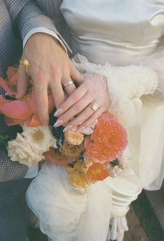 the bride and groom are holding each other's hands with their wedding rings on them