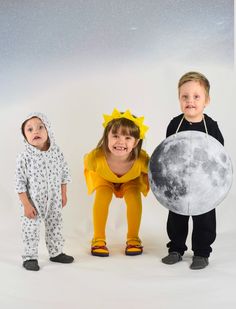 three children dressed up in costumes standing next to each other with the moon behind them