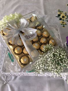 a clear box filled with chocolates and baby's breath flowers on a table