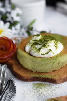 a green dessert with whipped cream and pesto sprinkles on a wooden cutting board