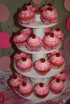 a three tiered cake with cupcakes and cherries on it