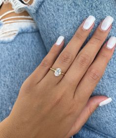 a woman's hand with white nails and a gold ring