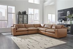 a living room with large windows and a sectional couch in front of a rug on the floor