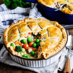 two pies with peas, carrots and broccoli in them on a wooden table