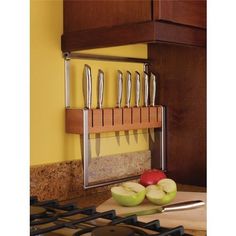 a knife holder with knives and apples on the counter top next to an oven door