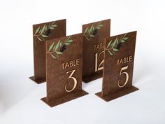 three wooden table numbers with olive leaves on them