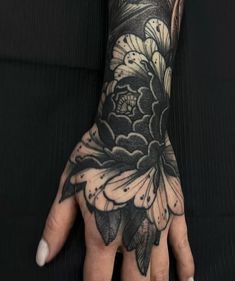 a woman's hand with black and white tattoos on it, showing the flowers