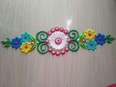 a colorful embroidered piece with flowers on it's side and green, yellow, red, blue, and pink beads