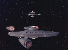 a star trek ship flying through the night sky with two other ships in the background