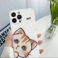 a person holding up a phone case with a cat painted on the back of it