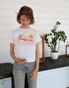 This tee features a hand-drawn design of a California license plate with a pink floral surfboard, palm tree, and the sun. DTG printed on a comfortable 100% cotton, high waisted women's tee. Sizing is accurate to fit. Floral Surfboard, California License Plate, Golden State Of Mind, California License, Graphic Tees For Women, Toddler Art, Girls T Shirt, Hand Drawn Design, Tees For Women