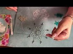 a woman is making snowflakes out of fabric and beads on a table top