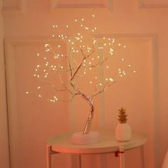 a white table topped with a pineapple tree next to a pink wall covered in lights