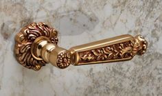 an ornate gold handle on a marble wall