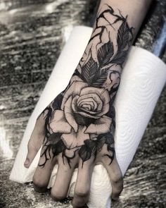 a black and white rose tattoo on the left hand