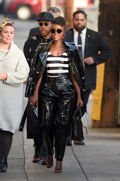 two women walking down the street wearing black leather pants and white shirt with stripes on them