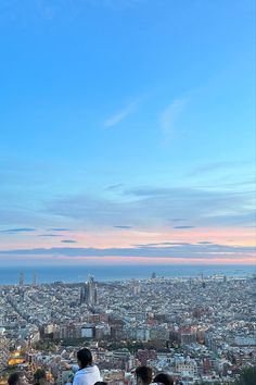 three people sitting on top of a hill overlooking the city