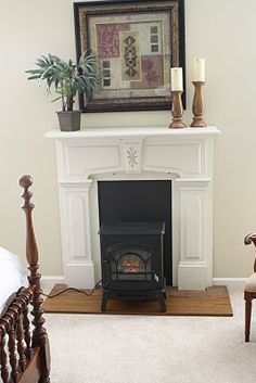 there is a fireplace in the corner of this room with two chairs and a bed