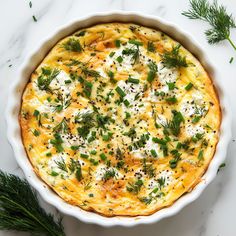 a casserole with cheese and herbs in a white dish on a marble surface