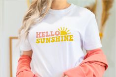 a woman wearing an orange and yellow hello sunshine t - shirt with her hands in her pockets