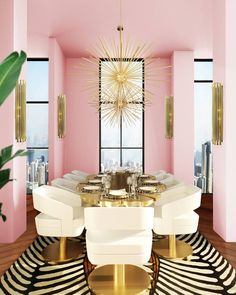 a dining room with pink walls and gold accents on the tables, chairs, and rugs