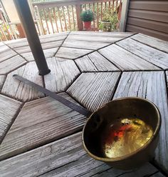 a metal bowl sitting on top of a wooden deck