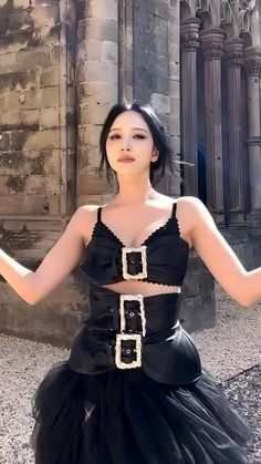 a woman in a black dress posing for the camera with her arms out and hands outstretched