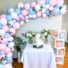 a table topped with balloons and flowers next to a cake on top of a table