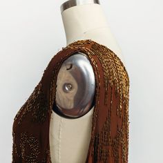 This is an insanely beautiful and intricately beaded antique 1920s silk flapper dress. The brown silk sleeveless dress is decorated with bugle beads and seed beads. The bugle beads are sewn to depict scenes of people and buildings while the seed beads form flowers. The scenes have an orientalist mood. The neck of the dress has bugle beads coming down in a triangular pattern with small houses on either side. Below that there is a figure on each side of the front of the dress, being over a bucket 1920s Embellished Sleeveless Flapper Dress, Silk Gatsby Style Fitted Flapper Dress, Beaded Fitted Sleeveless Flapper Dress, Vintage Sleeveless Sequin Flapper Dress, Fitted Silk Sleeveless Flapper Dress, Beaded Flapper Dress, Infinity Band, Triangular Pattern, West Chester Pa