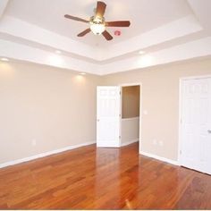 an empty room with hard wood floors and ceiling fan